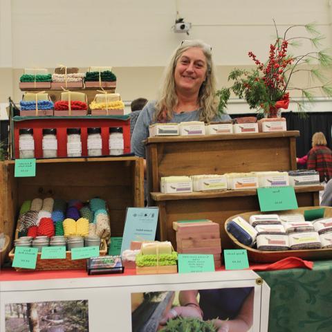 Woman standing behind booth with homemade soap